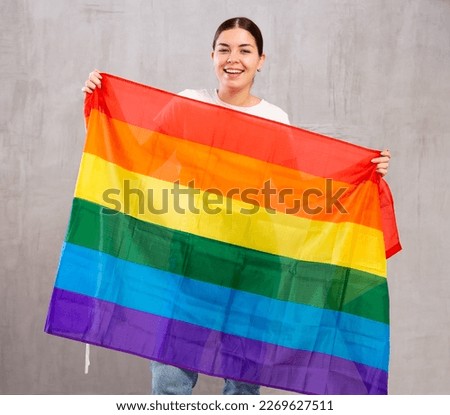 Young positive woman holding LGBT flag in her hands