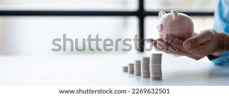 Person with pile of coins and piggy bank, money saving concept for future use and financial stability, salary management, personal finance, investment savings. Royalty-Free Stock Photo #2269632501