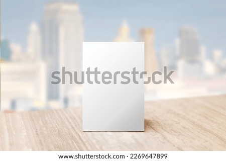 Mock up Label the blank menu frame in Bar restaurant. Stand for booklet with white sheet paper acrylic tent card on table wiht blurred city background can inserting the text or picture.