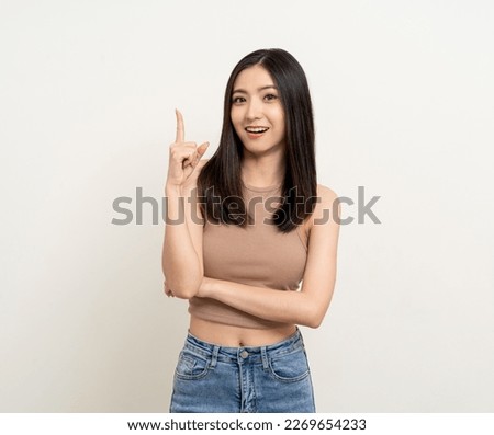 Happy beautiful young asian woman in brown shirt pointing finger to copy space. Smiling female lady with blank space. Asian cute Pretty people looking copy space text advertise