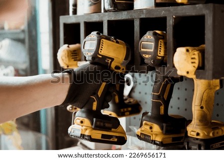 Motorcycle mechanic reaching for electric screwdriver or electric drill or impact tool on the wall to repair Motorcycle or car in garage.motorcycle maintenance and repair concept . selective focus Royalty-Free Stock Photo #2269656171