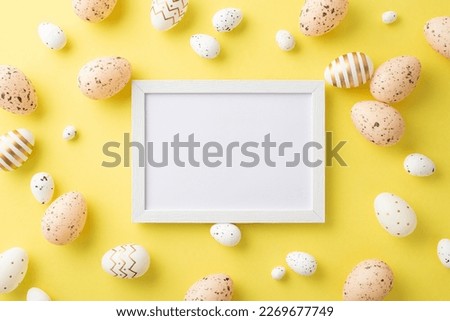 Easter decor concept. Top view photo of white photo frame and eater eggs on isolated yellow background with copyspace