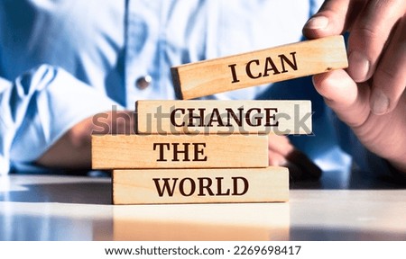 Close up on businessman holding a wooden block with "I Can Change the World" message