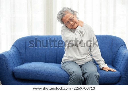 senior woman suffering from shoulder pain on sofa Royalty-Free Stock Photo #2269700713