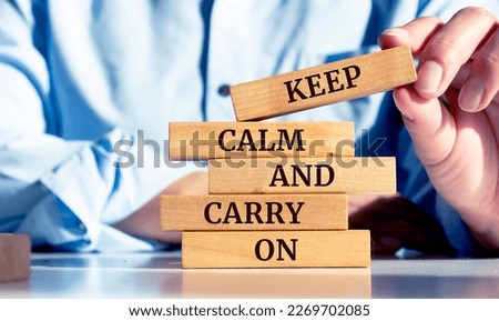 Close up on businessman holding a wooden block with "Keep calm and carry on" message