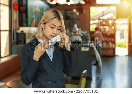 Close up portrait of beautiful business woman and puts on protective mask on her face of in the cafe shop.