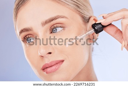 Face, beauty and skincare of woman with serum in studio isolated on a blue background. Dermatology cosmetics, thinking closeup and female model apply hyaluronic acid, retinol or essential oil product Royalty-Free Stock Photo #2269716231