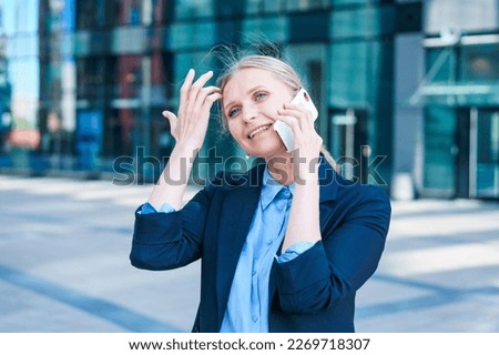 Business woman with phone near office. Portrait beautiful smiling girl in fashionable office clothes, talking on the phone while standing outdoors. Telephone communications. High quality image.
