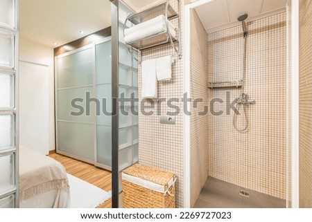 Laconic style bathroom with beige mosaic tiles and glass block wall with shower cabin sink. Concept of a hotel room or a cozy modern apartment