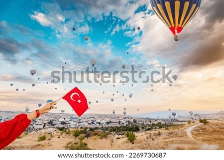 Experience the beauty and culture of Turkey through the eyes of a young woman as she watches the hot air balloons of Cappadocia soar and displays the Turkish flag.