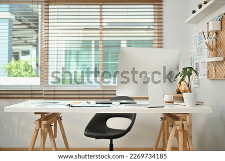 Modern workplace with computer monitor, wireframe, sketches of mobile application on screen, document and supplies on white table