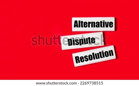 Three wooden blocks with the text ADR Alternative Dispute Resolution on a bright red background. Copy space
