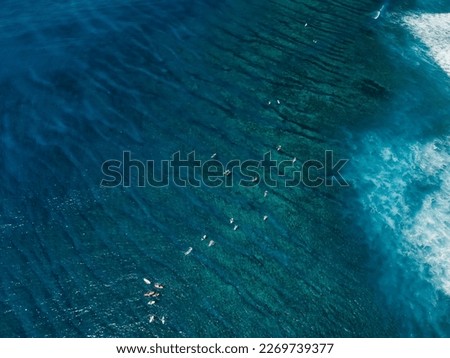 Aerial view of blue transparent ocean with surfers. Surfing spot in tropical island