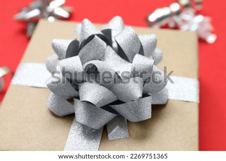 Gift box with shiny bow on red background, closeup