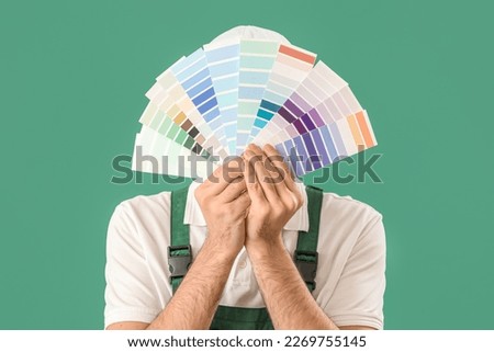 Male painter with color palettes on green background, closeup