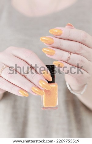 Female beautiful hand with long nails and a yellow orange nail polish