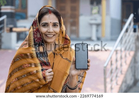 Indian rural woman showing smartphone screen. Royalty-Free Stock Photo #2269774169
