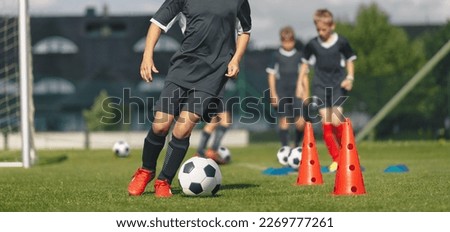 Group of School Kids at Soccer Training. Boys Kicking Classic Black and White Soccer Balls in Slalom Training Drill. Practice Session For Football Players at Summer Camp