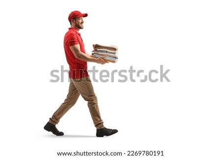 Delivery man carrying a pile of folded clothes and walking isolated on a white background

