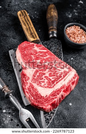 Butcher table with wagyu Rib Eye steak, raw beef meat. Black background. Top view