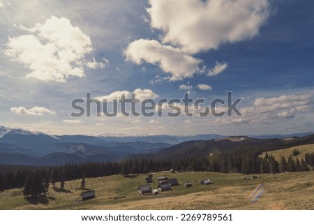 Hillside meadow with building log cabins site landscape photo. Nature scenery photography with hills on background. Ambient light. High quality picture for wallpaper, travel blog, magazine, article