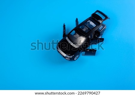 Black toy car with opened doors on blue backgroud. Concept buying new car.