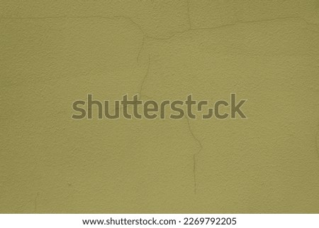 Closeup of greenish yellow painted wall with cracks