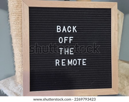 A sign saying back off the remote. The felt sign has removable letters than can be moved around to make whatever words or saying one wants. 