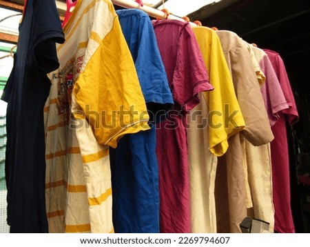 Imported Branded Clothes Mixed In Second-Hand Condition Are Hung In Rows With Hangers. Collection Used For Selling and Thrifting Trends. Colorful Clothes. There Are Linen, Cotton, Jeans, and Wool