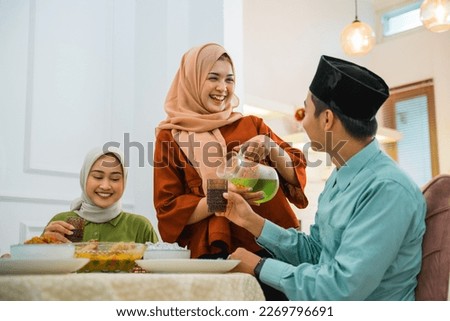 wife serves drink to husband while breaking fast at the dining table Royalty-Free Stock Photo #2269796691