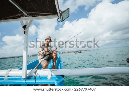 angler sitting at the end of the boat with thumbs up on a small fishing boat at sea Royalty-Free Stock Photo #2269797407