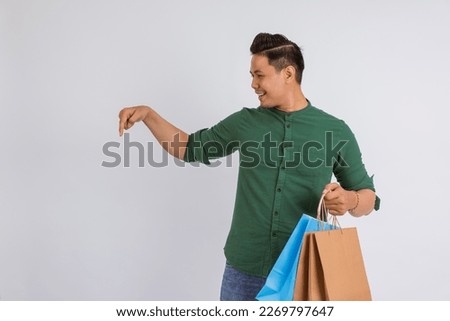 asian man pointing down while bring the shopping bags on isolated background