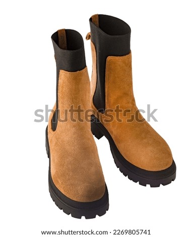 A pair of new fashionable boots with thick tractor soles. Suede leather shoes. Beige brown boots isolated on white background.