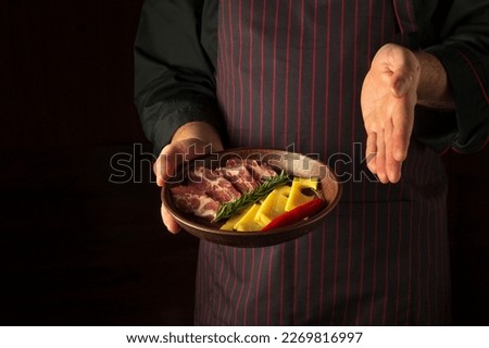 The cook presents a sliced steak with ham and cheese on a plate. The concept of serving dishes to order by a waiter with space for advertising on a black background