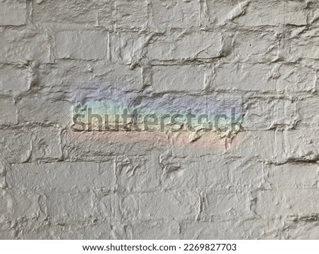 White brick wall texture with rainbow light. LGBT  symbol. Diversity society sign. Grunge background. Bricks image jpeg. LGBT+ rainbow colored. Freedom society concept. Street art on white wall.