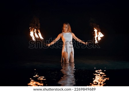 Caucasian woman dancing with fire in the water. Fire show at sea. Acrobatics on the beach. Yoga and relaxation at sunset. Spectacular circus performance. model body. Royalty-Free Stock Photo #2269849689