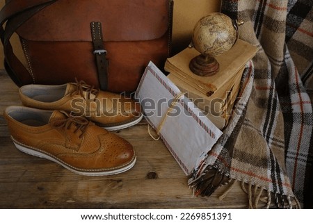 old nostalgic sentimental things, letters, stack of books, globe, shoes, vintage leather military satchel on table, checkered grandmother's plaid, family tree, home archive, memory of ancestors Royalty-Free Stock Photo #2269851391