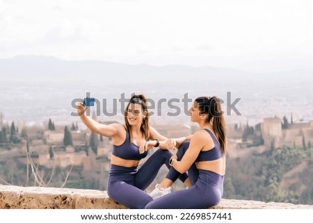 Sporty twin sisters take a selfie with the Alhambra in Granada Spain in the background