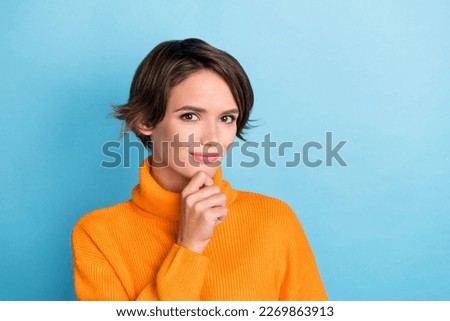 Photo of cute positive girl hand touch chin brainstorming empty space isolated on blue color background