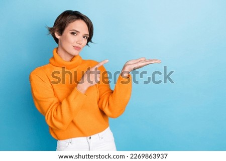 Photo portrait of lovely young lady palm hold copyspace product finger point wear trendy orange look isolated on blue color background
