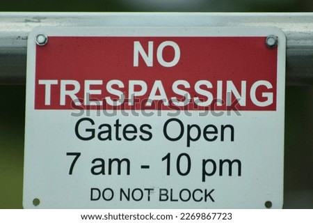 A sign that says "no trespassing gates open 7 am to 10 pm do not block".