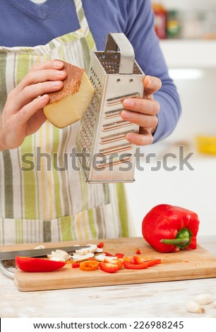 Man preparing vegetables and cheese for pizza.