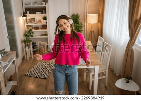 One woman young caucasian female teenager dancing alone at home with headphones on her head having fun while listen to the music happy smile real people copy space Royalty-Free Stock Photo #2269884919