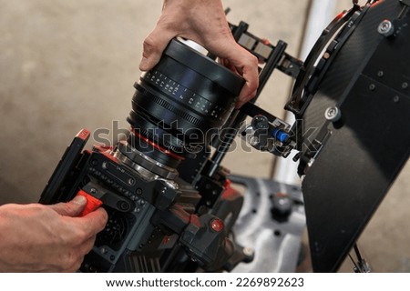 caucasian men hands change screw lens on professional movie camera