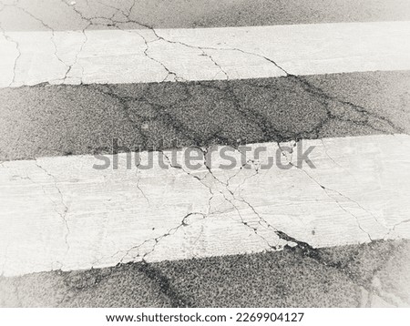 Detail of the road surface with crosswalks of an urban street with cracks
