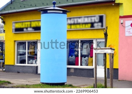 blank light blue advertising or Morris column. billboard sign. city street setting. cylindrical outdoor structure. blank commercial poster. marketing concept. diminishing perspective. 