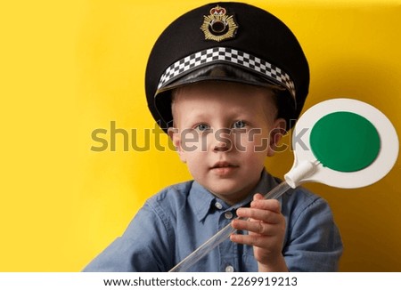 Boy in a cap of a policeman showing a green traffic light on a yellow background