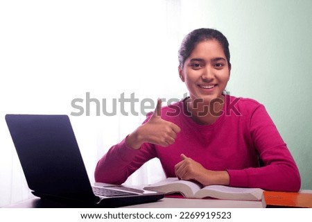 A YOUNG TEENAGER SHOWING THUMBS UP DURING ONLINE CLASS