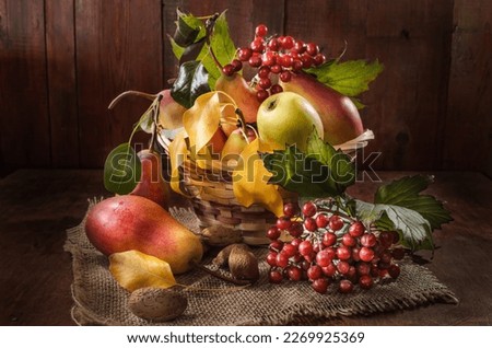 Ripe pear and a bunch of viburnum berries on a dark wooden background in a rustic style