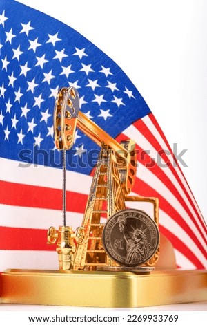 Gold oil pump and one dollar coin against the background of the Stars and Stripes American flag